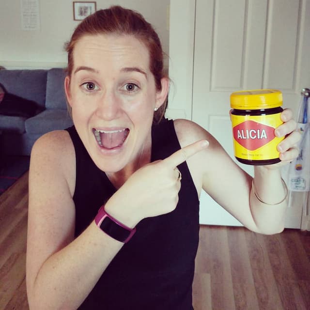 Alicia smiling and pointing at Vegemite jar